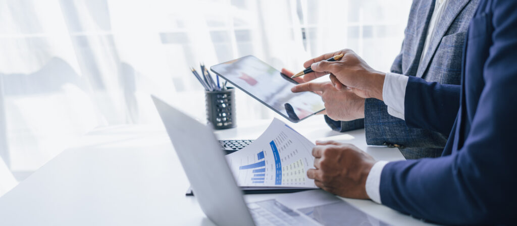 Two professionals collaborating over a tablet displaying Syspro Sales Analysis data, reviewing business insights together during a planning or analysis session.